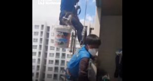 woman cuts building workers' rope