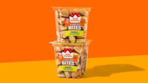 Two clear plastic tubs of King's Hawaiian Shake'n Bites Banana-flavored snack stacked against an orange and yellow background.