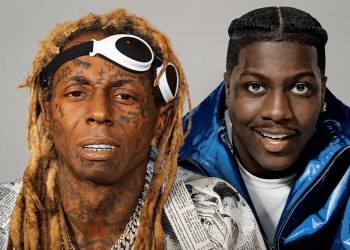 Two men pose closely for a photo: left man with blonde dreadlocks, tattoos, and white sunglasses on his head; right man in a shiny blue jacket smiles at the camera.