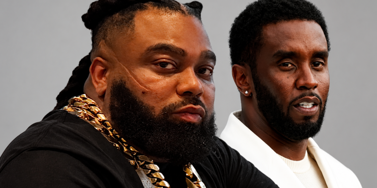 Two men pose together; left man wears heavy gold chains and has braided hair, right man wears a white blazer against a gray background.