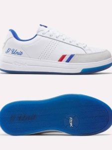 - Baller Alert White sneaker with blue lining and red/blue stripes, shown in side profile with laces; blue sole visible from the bottom for contrast and tread.