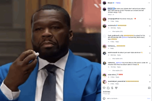 Close-up of a man in a bright blue suit and gray tie, adjusting a chain near his mouth in an Instagram post.