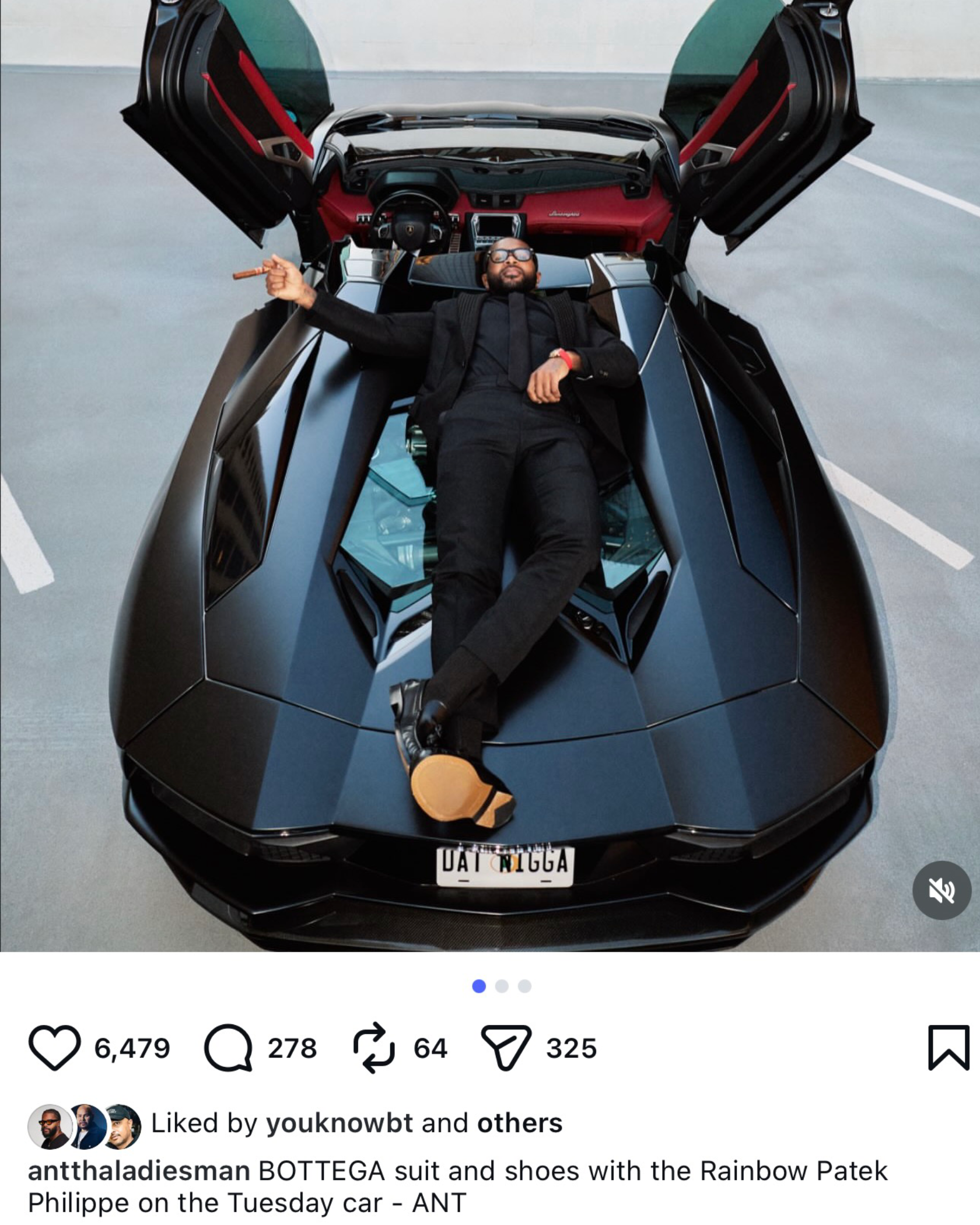 Ant Wilson lying on his matte black Lamborghini Aventador Roadster in a black Bottega suit